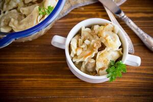 cooked dumplings with potatoes and fried onions on a wooden table. photo