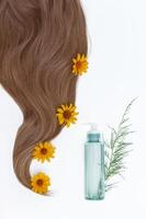 sano y hermosa cabello. cosmético petróleo y flores para pelo en un blanco antecedentes. pelo cuidado. Copiar espacio para texto foto