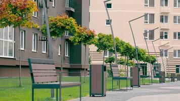 The outbuilding area near the new buildings is equipped with a green landscape and modern benches and lanterns. Rest area near residential complex. video