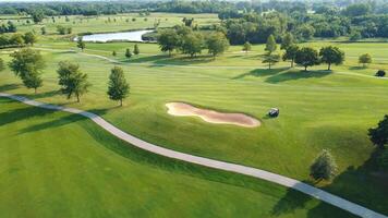 antenn se av en golf kurs. en stor grön gräsmatta med infrastruktur för spelar golf. spelare i golf bilar. video