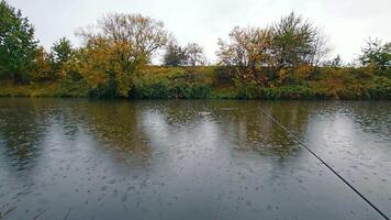 Fishing on the river in rainy weather. Landscape of cloudy weather on the river bank. Raindrops fall into the water. video