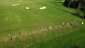 topp se av de golf kurs, spelare och anställda av de golf klubb är på de kurs, alla är håller på med deras egen sak. antenn se av de grön golf kurs. video