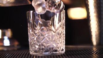 barman pone hielo en un vaso. haciendo un alcohólico cóctel. video