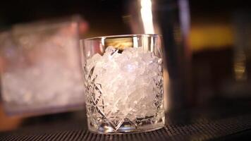 barman pone hielo en un vaso. haciendo un alcohólico cóctel. video