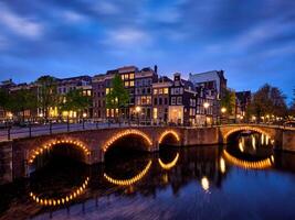 Ámsterdam canal, puente y medieval casas en el noche foto