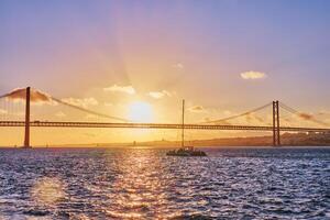 View of 25 de Abril Bridge over Tagus river on sunset. Lisbon, Portugal photo