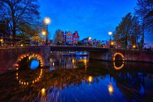 Amsterdam canal, puente y medieval casas en el noche foto