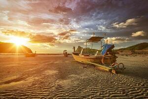 largo cola barco a playa en puesta de sol foto