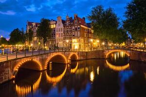 Amsterdam canal, puente y medieval casas en el noche foto