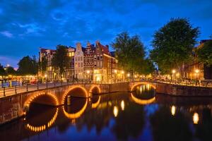 Amsterdam canal, puente y medieval casas en el noche foto