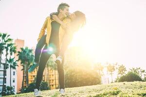 Happy lesbian couple piggyback having fun and laughing while looking each other eye in a park outdoor - Lgbt, relationship, happiness concept photo