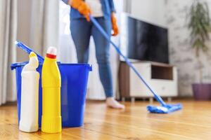 A young woman washes the floor with a mop in the living room photo