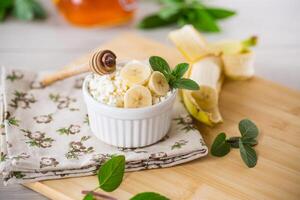 crumbly organic cottage cheese with honey and bananas in a ceramic bowl photo