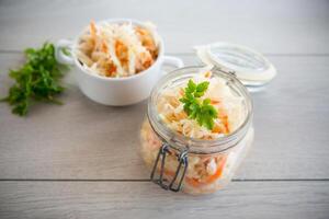 Sauerkraut with carrots and spices in a glass jar photo