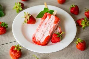 homemade strawberry ice cream on a stick in a plate with strawberries photo