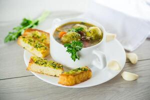 Hot cooked soup with Brussels sprouts, vegetables and croutons, in a plate. photo