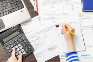 Woman using calculator for calculate domestic bills at home photo