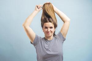 Beautiful brown-haired woman brushing her beautiful shiny hair with hairbrush photo