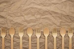 Set of wooden forks and spoons on crumpled paper background photo