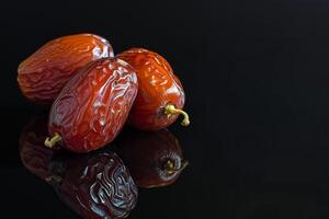 AI generated Juicy dates on a black reflective background photo