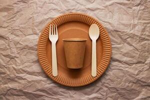 Wooden fork, spoon on cardboard plate on crumpled paper background photo