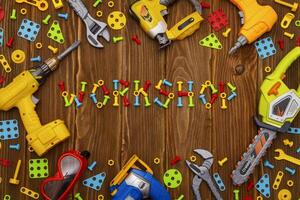 Toy tools, bolts and nuts with text WORKSHOP on wooden background photo