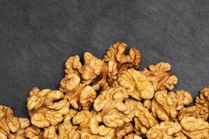 Walnuts. Walnut kernels on dark black stone background. Top view, flat lay photo