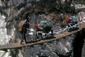 Sherpa and yaks crossing suspension bridge photo