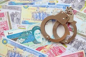 Police handcuffs with iranian money bills rials. The concept of crime and offenses or fraud photo