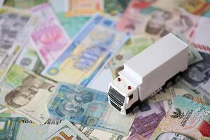 Delivery truck on many banknotes of different currency. Background of trucking or moving concept photo