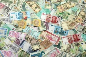 Many banknotes of different currency. Background of big amount of random money bills photo