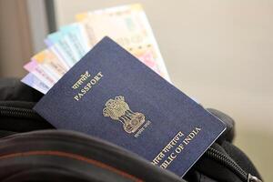 Blue Indian passport with money and airline tickets on touristic backpack photo