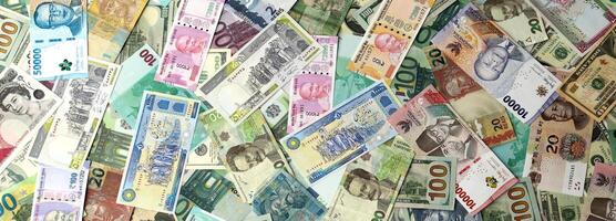 Many banknotes of different currency. Background of big amount of random money bills photo