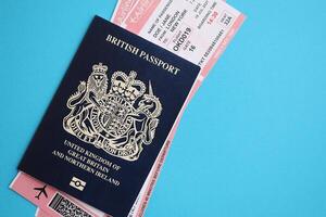 Blue British passport with airline tickets on blue background close up photo