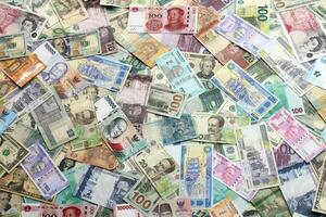 Many banknotes of different currency. Background of big amount of random money bills photo