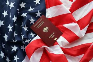 Red German passport of European Union on United States national flag background close up photo