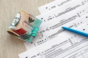 Annual Individual Income Tax Return forms with pen and indonesian rupiah bills photo