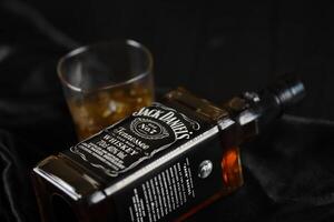 KYIV, UKRAINE - MAY 4, 2022 Jack Daniels original alcohol bottle on wooden table with black fabric photo