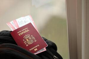 Red Spanish passport of European Union with airline tickets on touristic backpack photo