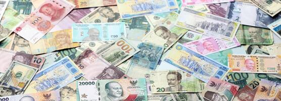 Many banknotes of different currency. Background of big amount of random money bills photo