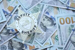 KYIV, UKRAINE - MARCH 9, 2024 US Deputy Sheriff badge on many US hundred dollar bills photo