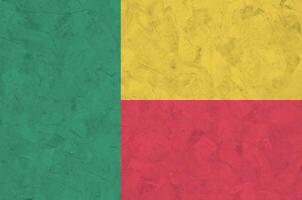 Benin flag depicted in bright paint colors on old relief plastering wall. Textured banner on rough background photo