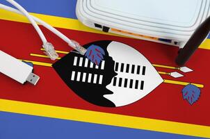 Swaziland flag depicted on table with internet rj45 cable, wireless usb wifi adapter and router. Internet connection concept photo
