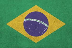 Brazil flag depicted in bright paint colors on old relief plastering wall. Textured banner on rough background photo