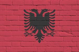 Albania flag depicted in paint colors on old brick wall. Textured banner on big brick wall masonry background photo