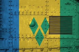 Saint Vincent and the Grenadines flag depicted on side part of military armored tank closeup. Army forces conceptual background photo