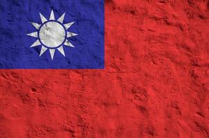 Taiwan flag depicted in bright paint colors on old relief plastering wall. Textured banner on rough background photo