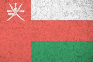 Oman flag depicted in bright paint colors on old relief plastering wall. Textured banner on rough background photo