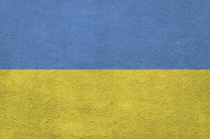 Ukraine flag depicted in bright paint colors on old relief plastering wall. Textured banner on rough background photo