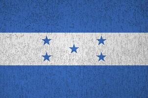 Honduras flag depicted in bright paint colors on old relief plastering wall. Textured banner on rough background photo